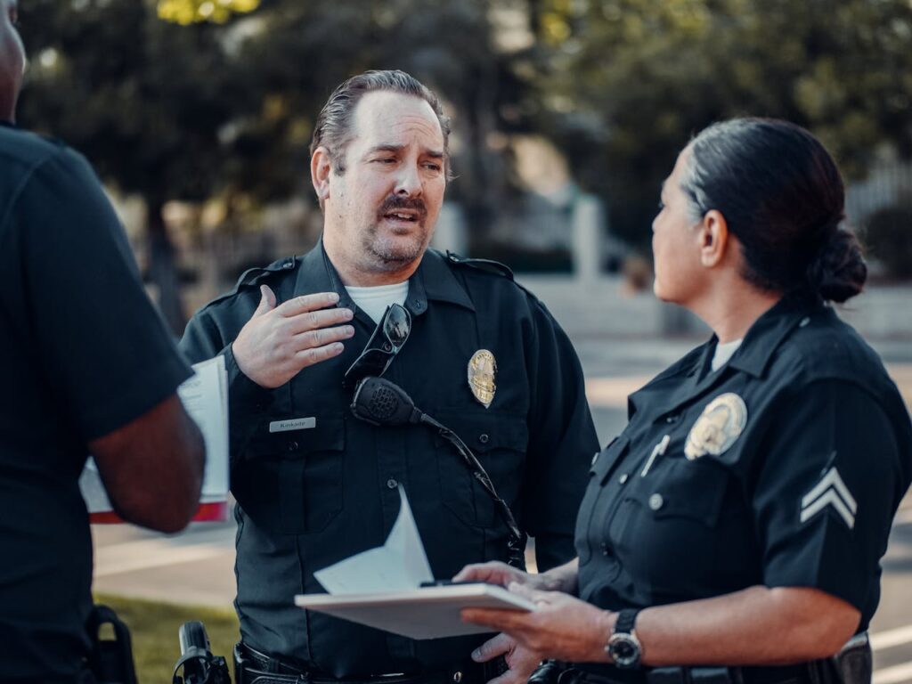 Three police officers engage in conversation outdoors, showcasing teamwork.